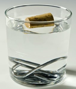 Glass of water with objects showing water displacement